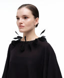 Goose feather collar by MOSAÏKA styled on model from side creating soft sculptural volume around neckline