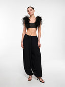 Black strapless crop top by MOSAÏKA styled with feather hem pants creating expressive silhouette