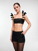 Black strapless crop top by MOSAÏKA styled with detachable leaf straps adding graphic shoulder accent